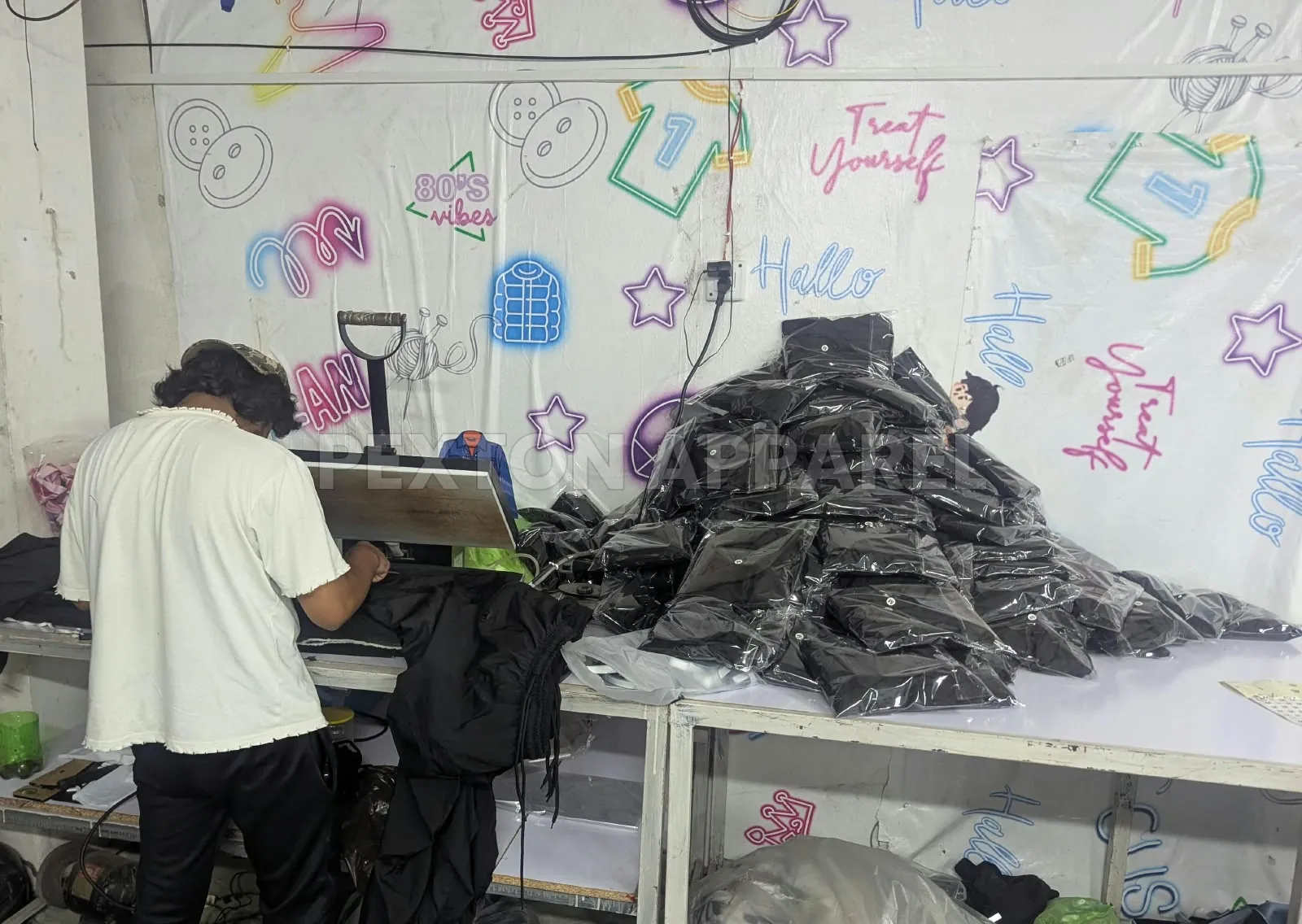 Heat press applying logo transfers to garments at Pexton Apparel